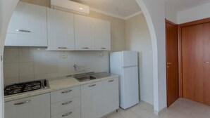 Een keuken met witte kastjes, een witte koelkast en een gasfornuis.