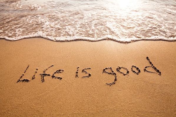 A beach with the words "Life is good" written in the sand.