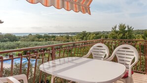 A balcony with a view of a pool and greenery, featuring a white table and chairs. - Apartment bay view with great sea view in Porec, only 300m from the beach (Porec)
