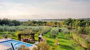 A pool with a pergola and outdoor furniture, surrounded by lush greenery and a view of the sea. - Apartment bay view with great sea view in Porec, only 300m from the beach (Porec)