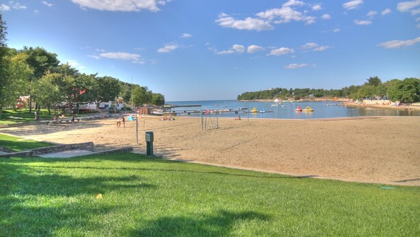A beach with a volleyball net, a sandy area, and a water body. - Apartment bay view with great sea view in Porec, only 300m from the beach (Porec)