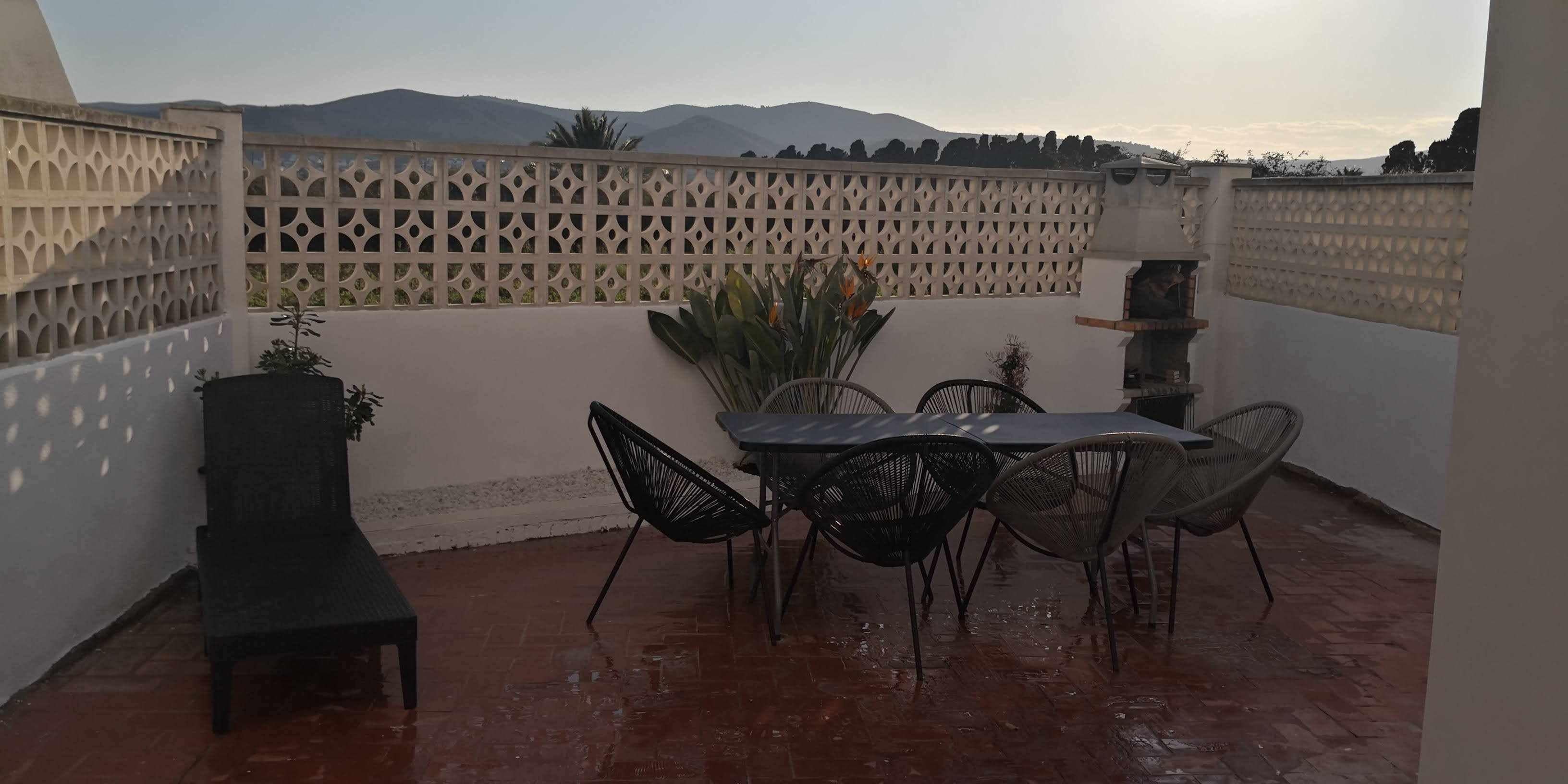 A patio with a table and chairs, a bench, and a decorative fence.