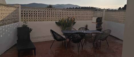 A patio with a table and chairs, a bench, and a decorative fence.