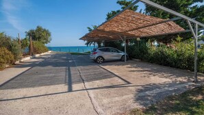 Un estacionamiento techado con un automóvil, vista al mar y cielo despejado.