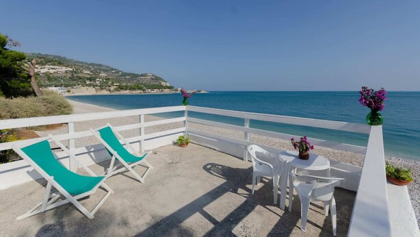 A balcony with white chairs and a table, overlooking a beach and clear blue sea. - Miramare House - Trilo 4 B (Mattinata)
