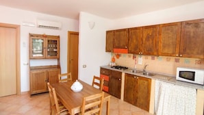 Una cucina compatta con mobili in legno, un tavolo da pranzo con sedie, un forno a microonde e un fornello a gas.