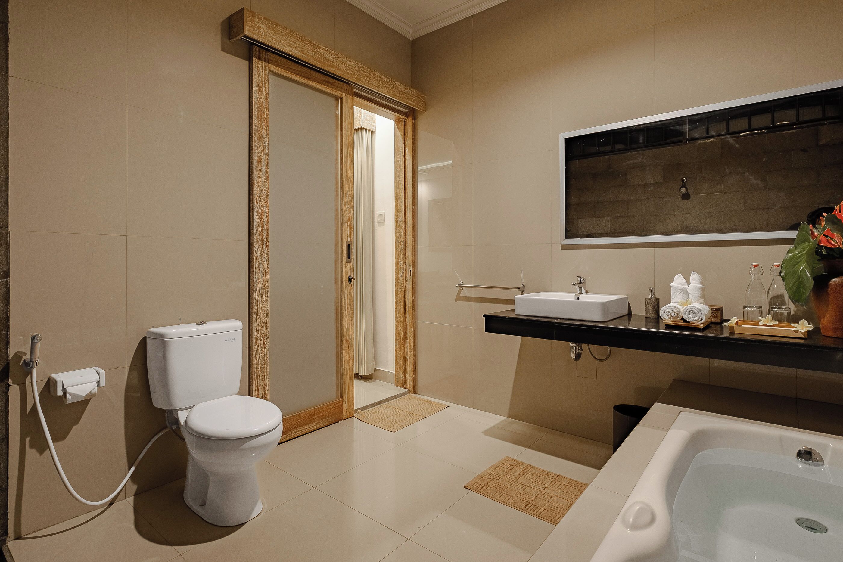 A modern bathroom with a toilet, bidet, sink, and bathtub.