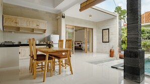 A spacious kitchen with wooden cabinets and a dining area with a table and chairs. - Puri Sedana Ubud Villa (Ubud)