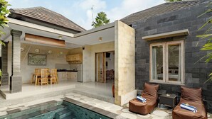 A modern house with a swimming pool, a dining area, and two lounge chairs. - Puri Sedana Ubud Villa (Ubud)