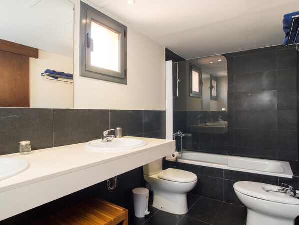 A modern bathroom with a white sink, a toilet, and a bathtub.