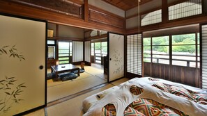 A traditional Japanese room with tatami flooring, shoji screens, and a futon bed. - Masuya Ryokan (Aoki)