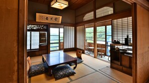 A traditional Japanese room with tatami flooring, a low table, and shoji screens. - Masuya Ryokan (Aoki)