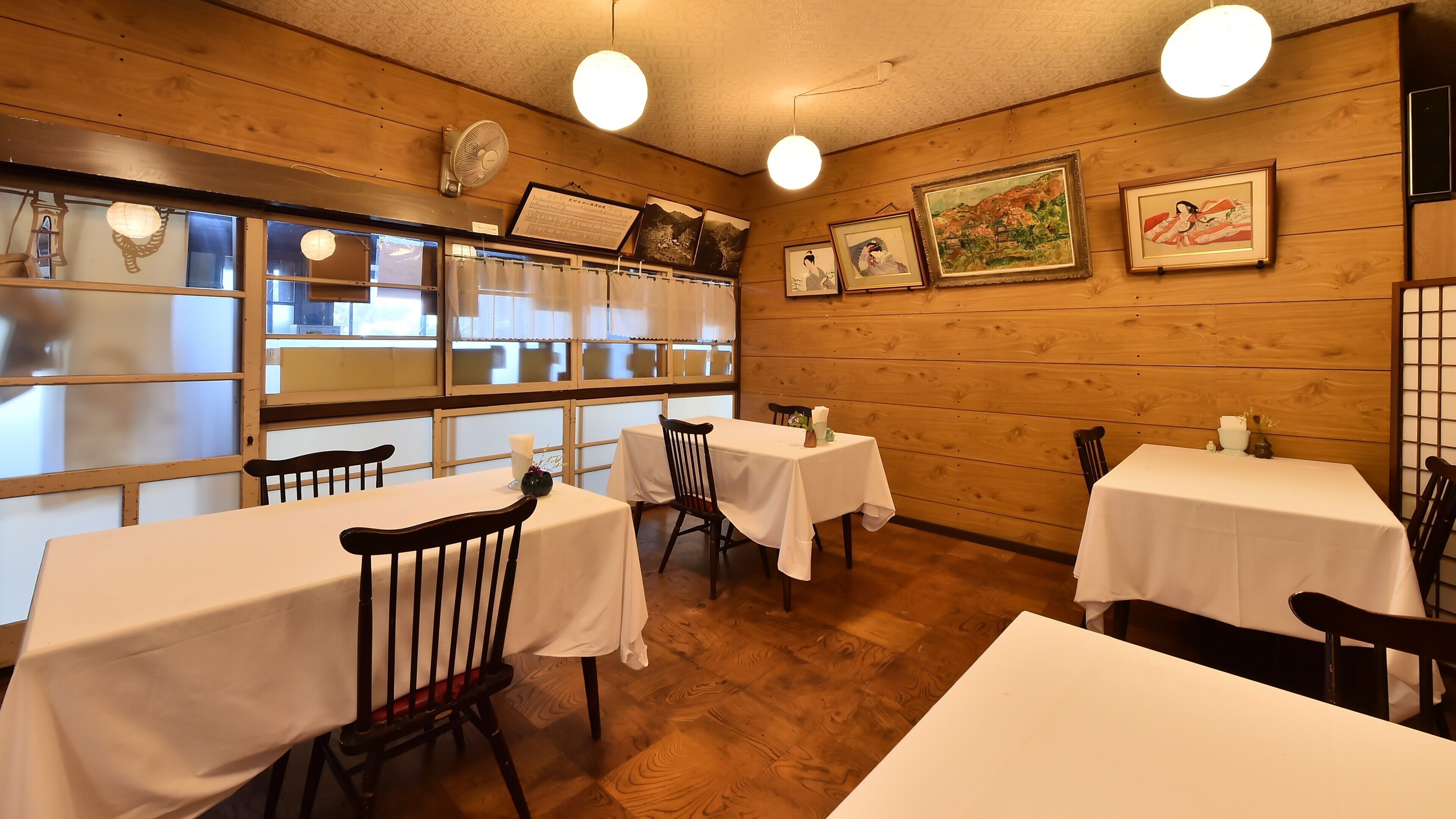 Interior de restaurante con paredes de madera, varias mesas y sillas.