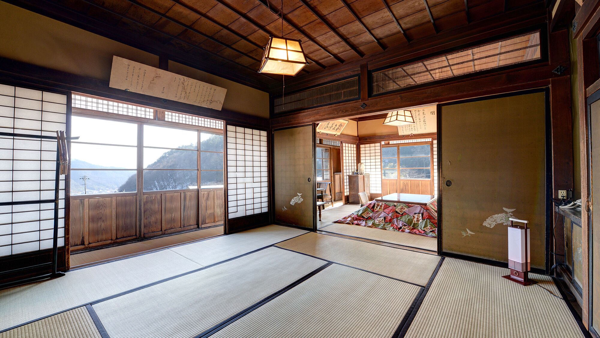 Una habitación japonesa tradicional con suelo de tatami, puertas correderas y vistas al exterior.