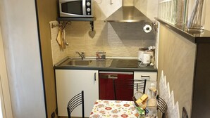 A compact kitchen with a microwave, sink, and a small dining area with chairs.