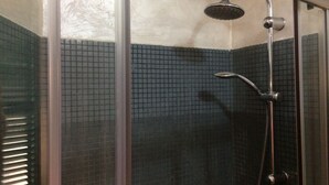 A shower with a handheld showerhead and a wall-mounted faucet.