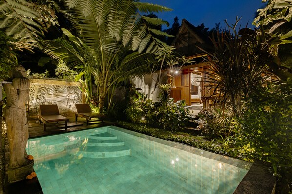 A swimming pool surrounded by lush greenery and a wooden structure. - Moringa Ubud Villa (Ubud)
