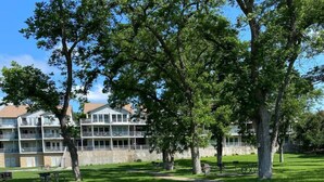 A pathway leading to a building with multiple balconies, surrounded by trees and grass. - Guadalupe Dew Drop Inn |Pools | Monthly Discounts (New Braunfels)