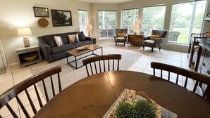 A spacious living room with a dining table, chairs, a sofa, and a ceiling fan. - Guadalupe Dew Drop Inn |Pools | Monthly Discounts (New Braunfels)