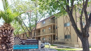 A multi-story building with a sign for Waterwheel Resort Condominiums. - Guadalupe Dew Drop Inn |Pools | Monthly Discounts (New Braunfels)