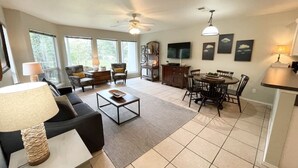 A spacious living room with a sofa, coffee table, and dining area with chairs and a table. - Guadalupe Dew Drop Inn |Pools | Monthly Discounts (New Braunfels)