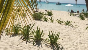 Ein Strand mit Palmen, klarem blauen Wasser und einigen Booten.