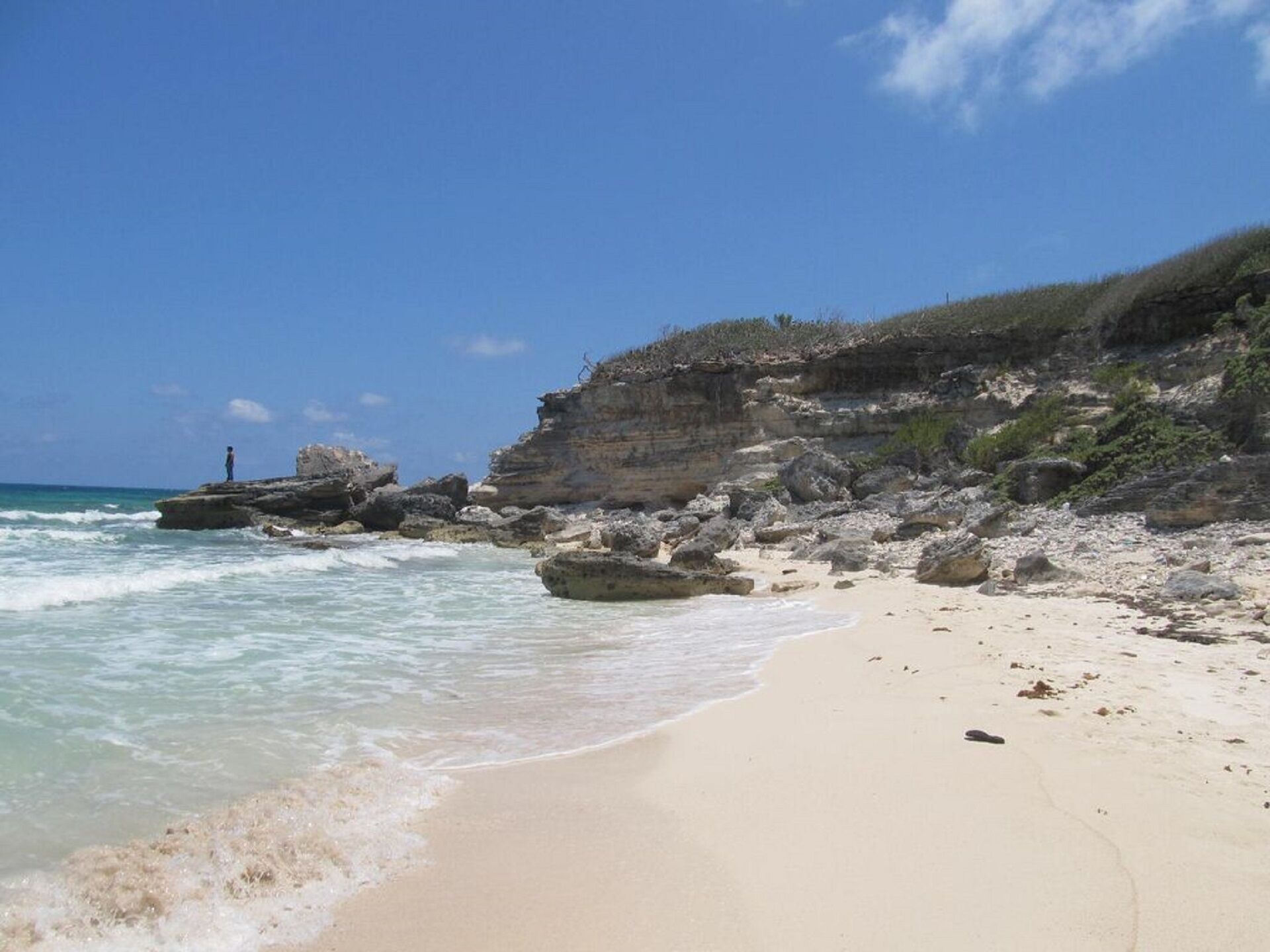 Ein Strand mit felsigen Klippen und klarem, blauem Wasser.