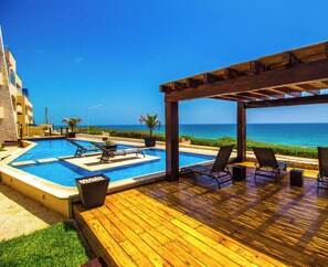 A wooden deck with a pool, lounge chairs, and a view of the ocean. - New Luxury Ocean Front Villa 😎Spectacular Caribbean Ocean Views  (Isla Mujeres)