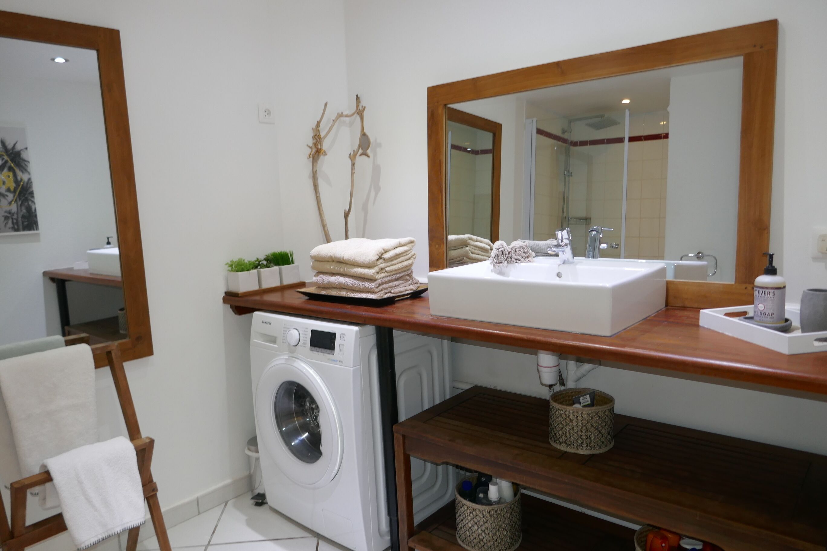 A bathroom with a washing machine, a sink, and a mirror.
