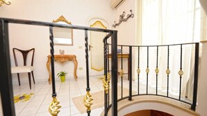 Eine Treppe mit schwarzer Geländer und goldenen Akzenten führt zu einem Raum, der einen Sessel, einen kleinen Tisch und einen Blumentopf beinhaltet.