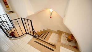 Eine Treppe mit schwarzem Metallgeländer und einer Wandleuchte.