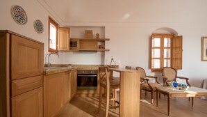 A kitchen with wooden cabinets, a built-in oven, and a dining area with a table and chairs.