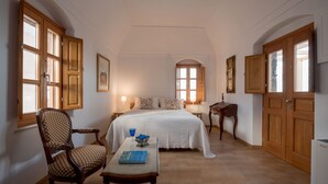 A bedroom with a large bed, wooden wardrobe, and a chair.