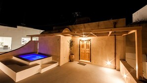 A modern outdoor pool area with a wooden pergola, a wooden door, and a potted plant.