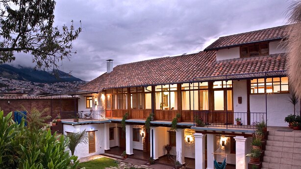 A two-story house with a tiled roof, multiple windows, and a balcony.