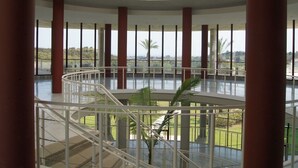 A spacious atrium with a central staircase, large windows, and a view of greenery outside. - Parque Botanico Holiday Rentals (Benahavis)