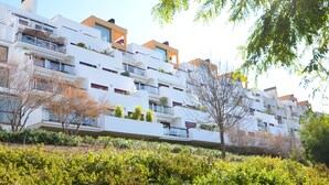 A modern multi-story residential building with balconies, surrounded by greenery and trees. - Parque Botanico Holiday Rentals (Benahavis)