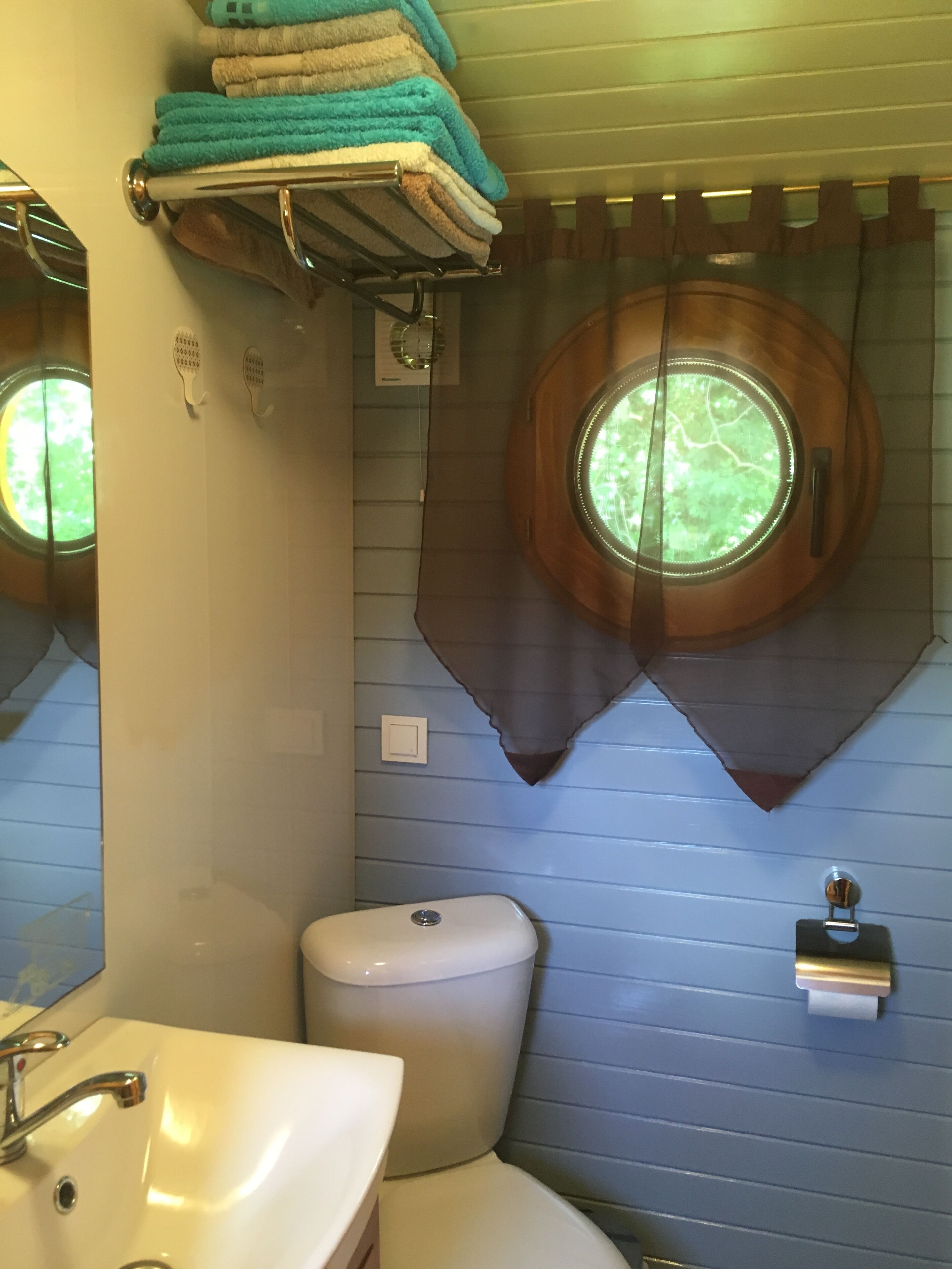 Ein Badezimmer mit Toilette, Waschbecken und einem Fenster mit Vorhang.