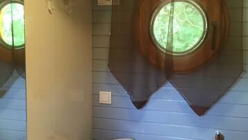 Een badkamer met toilet, wastafel en een raam met gordijn.