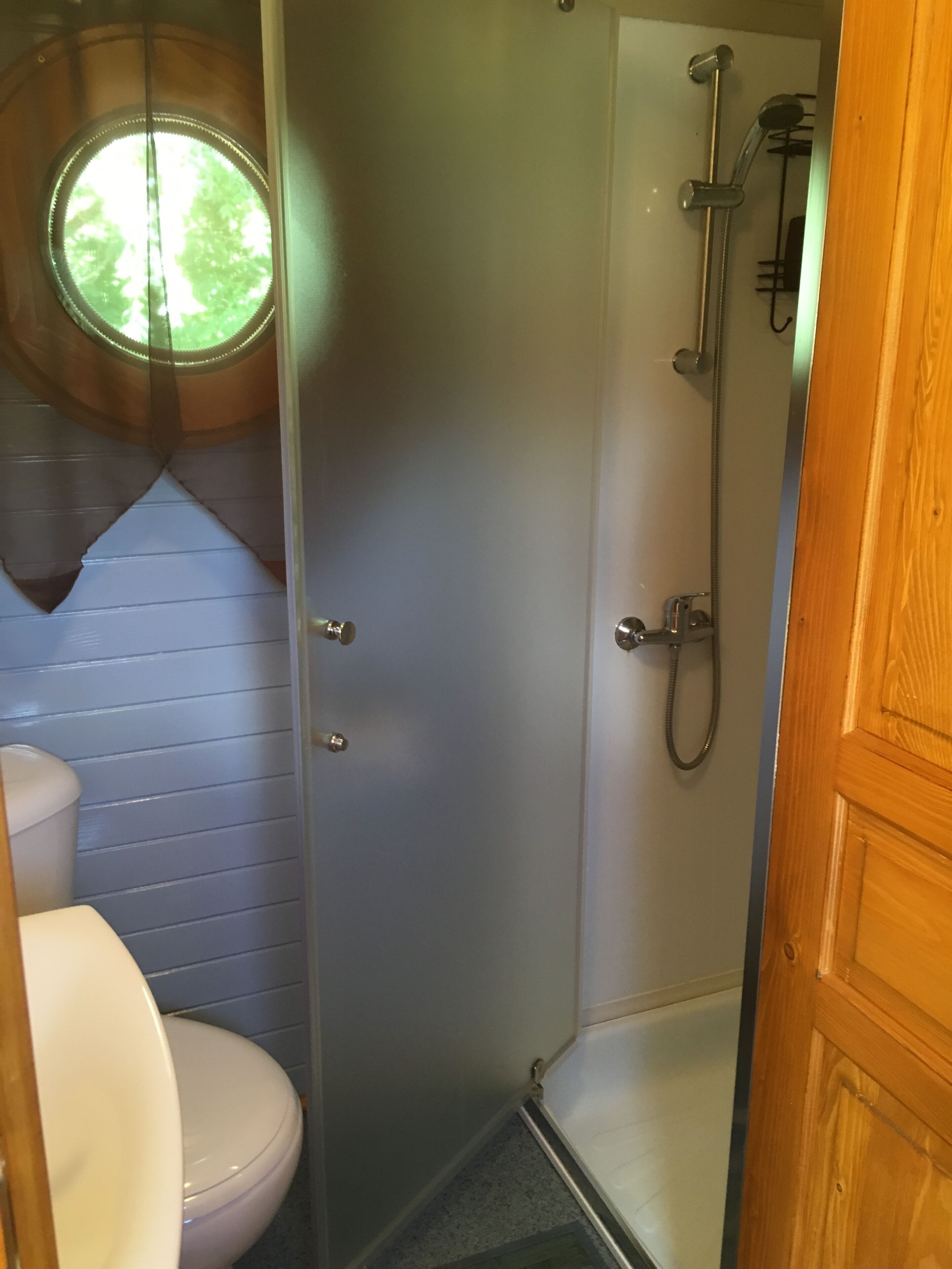Une salle de bain avec des toilettes, une douche et une fenêtre.