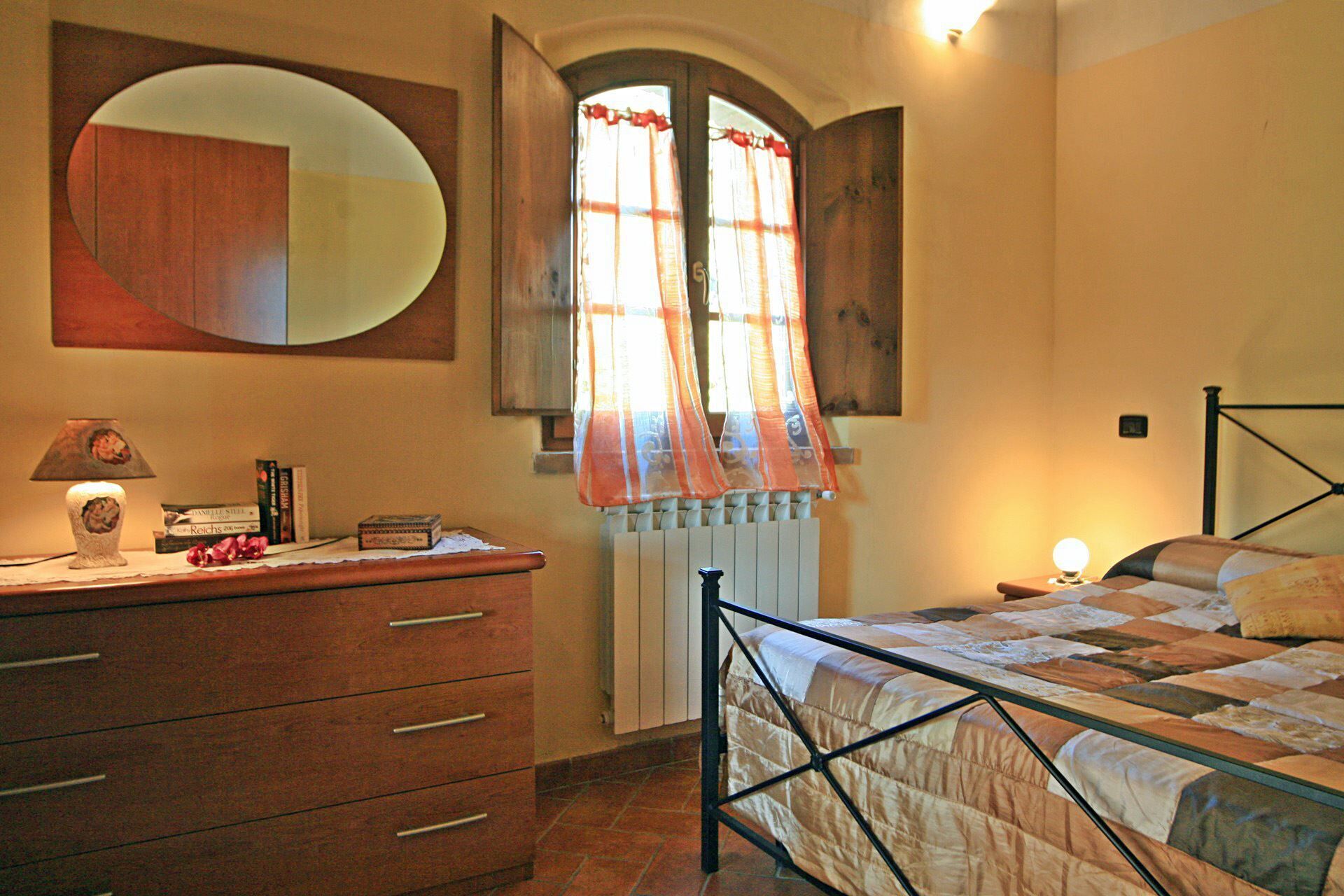 A bedroom with a bed, a dresser, a mirror, and a window with curtains.
