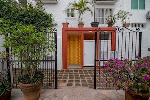 Traditional Spanish-style building with a gated entrance and potted plants.