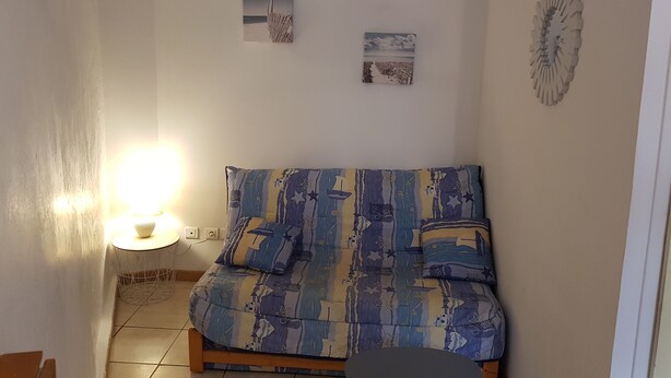 Een woonkamer met een bank, een bijzettafeltje en twee foto's aan de muur.