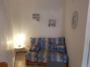 Un salon comprenant un canapé, une petite table et deux tableaux accrochés au mur.