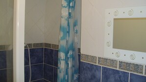 Een badkamer met douchegordijn, betegelde wanden en een decoratieve spiegel.