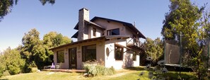 A two-story house with a stone chimney, a balcony, and a satellite dish.