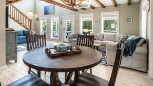 Een ruime woonkamer met een ronde houten tafel, een bank en een trap naar een hoger niveau.