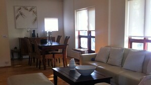 A spacious living room with a sofa, ottoman, and a dining area with chairs and a table. - Great villa in the center of Reykjavik on the most beautiful valley of the town (Unknown)