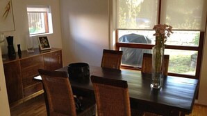 A dining area with a dark wooden table, wicker chairs, and a vase with dried flowers. - Great villa in the center of Reykjavik on the most beautiful valley of the town (Unknown)