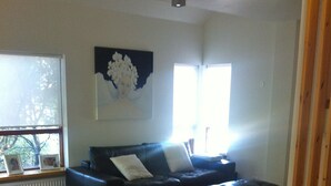 A living room with a sofa, ottoman, and a table with a bowl and candle. - Great villa in the center of Reykjavik on the most beautiful valley of the town (Unknown)